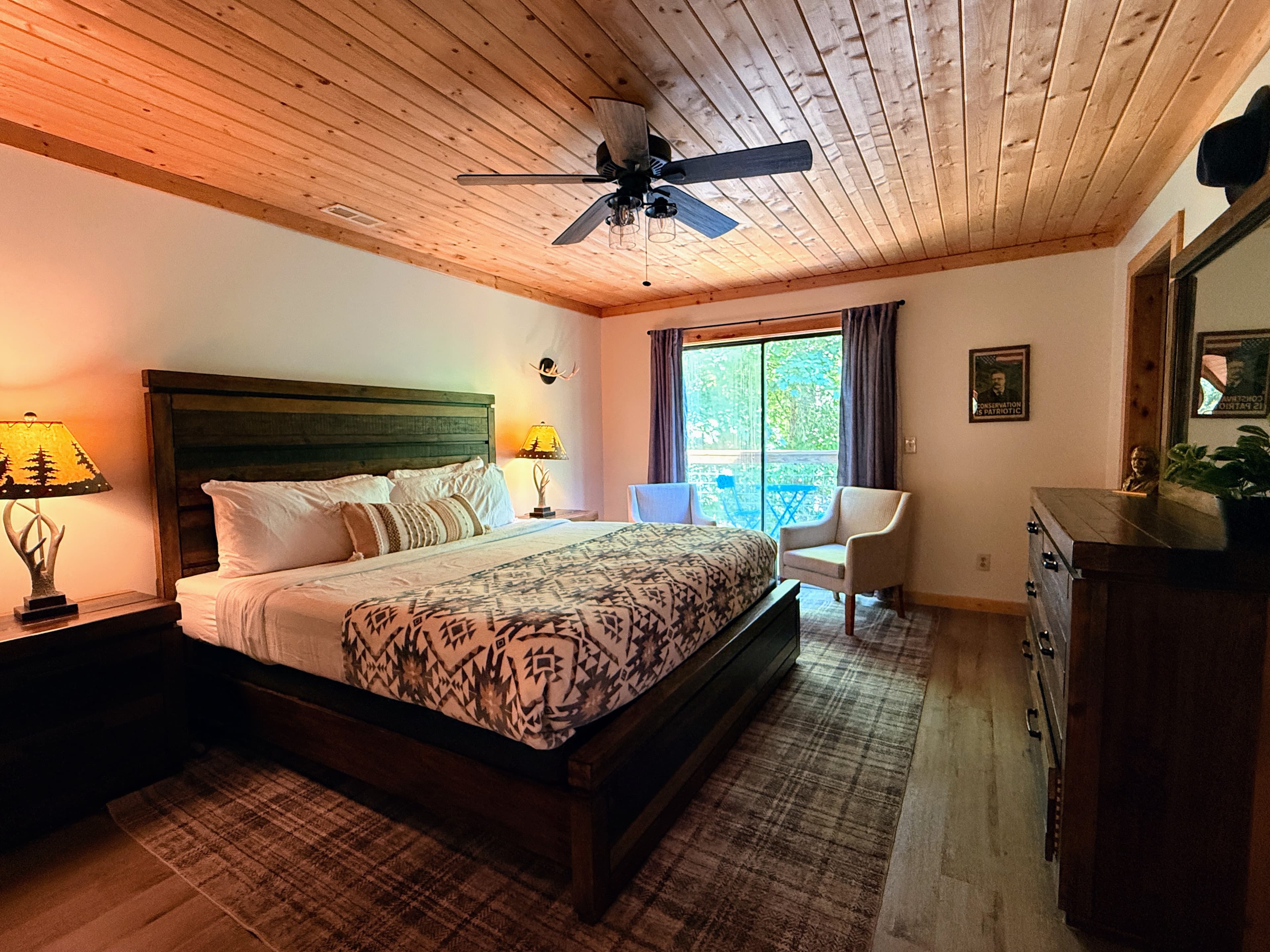 Spacious master bedroom in The Teddy with a king-sized log bed, luxury linens, and private access to the balcony at Frontier Hall.