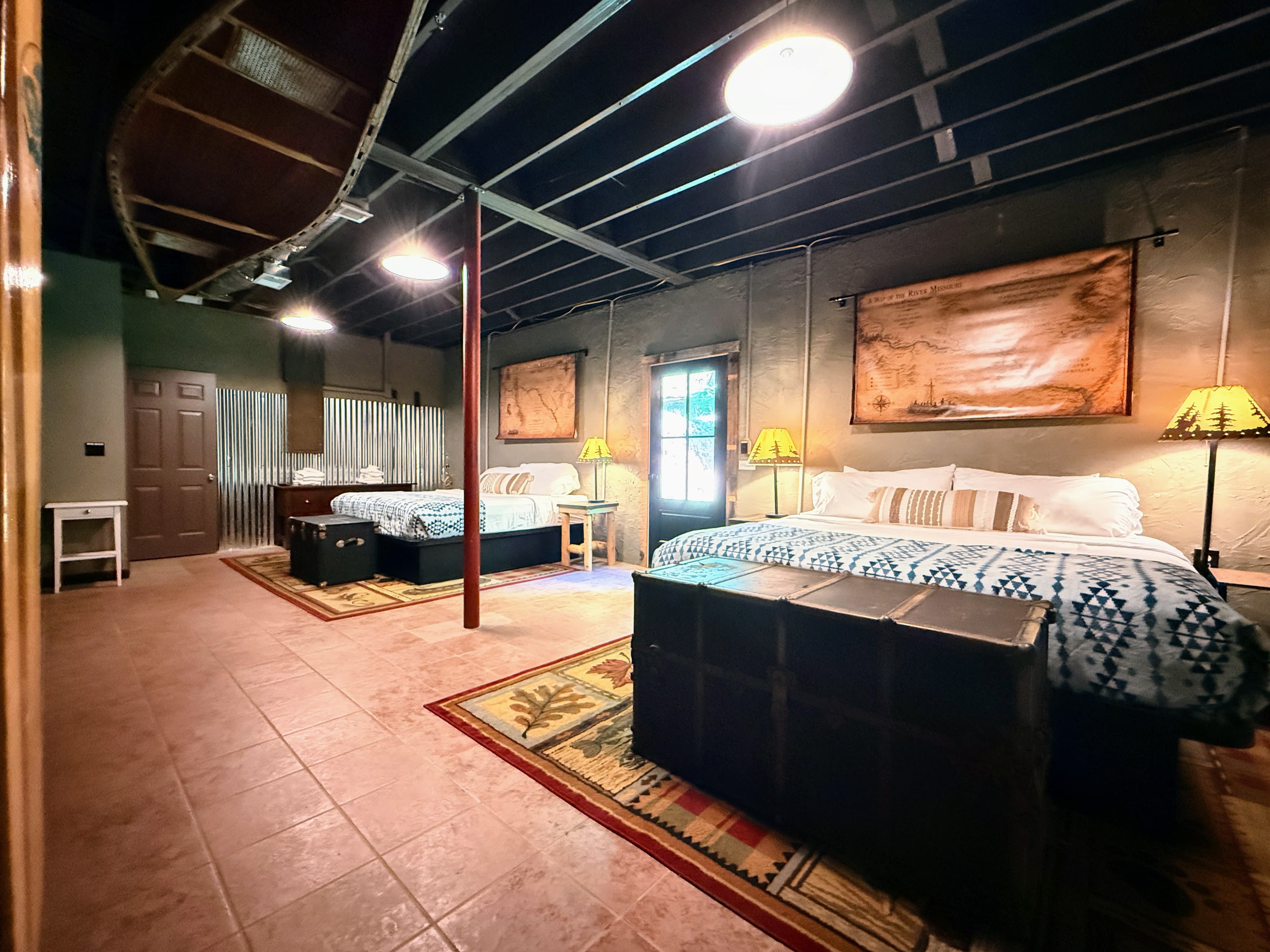 Lewis and Clarke camp guest bedroom at The Teddy featuring American explorer-themed decor, a king-sized bed, and views of the surrounding woods