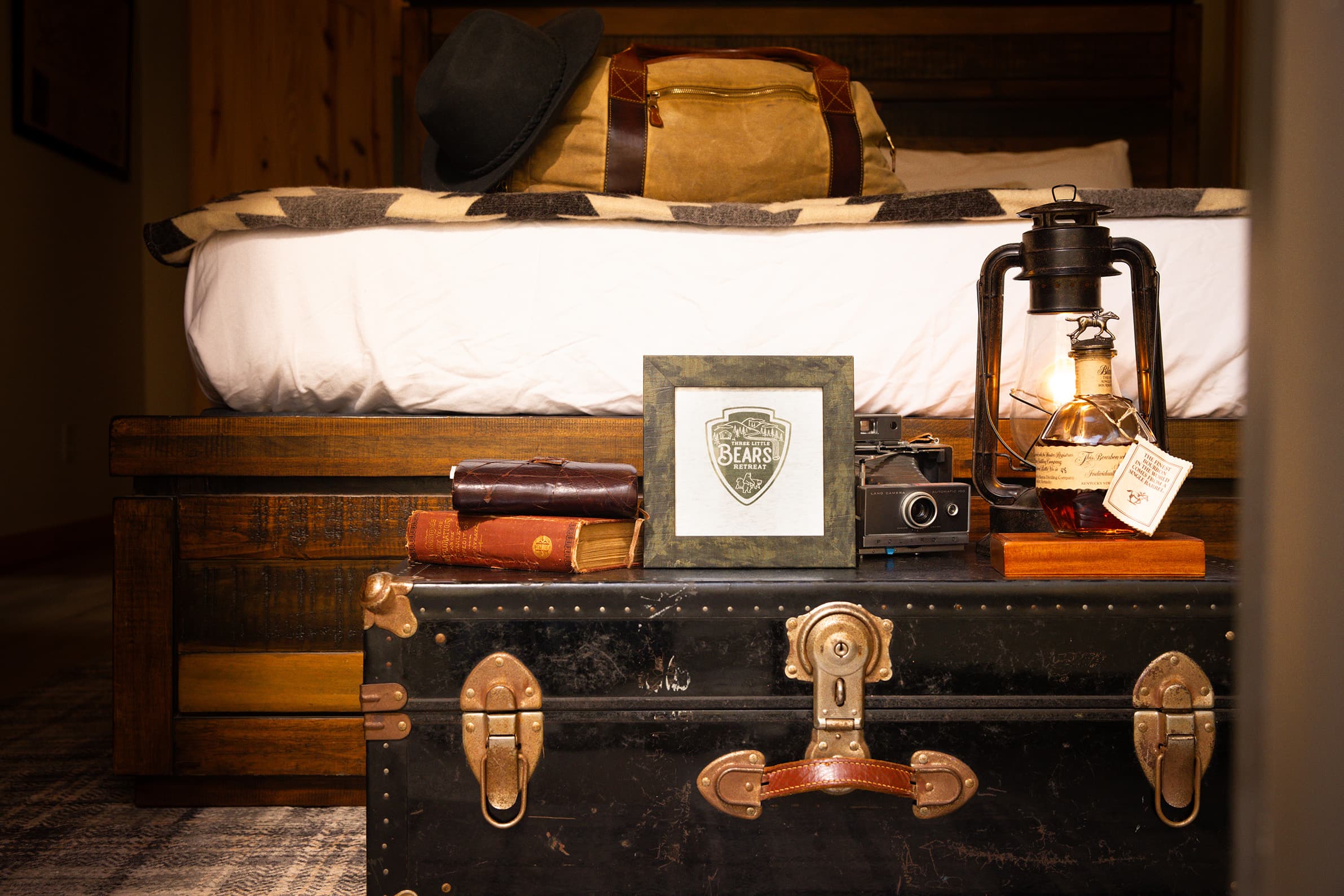 The Teddy master bedroom staged for adventure with a vintage map of the Great Smoky Mountains, a compass, and a cozy wool blanket on a king-sized log bed