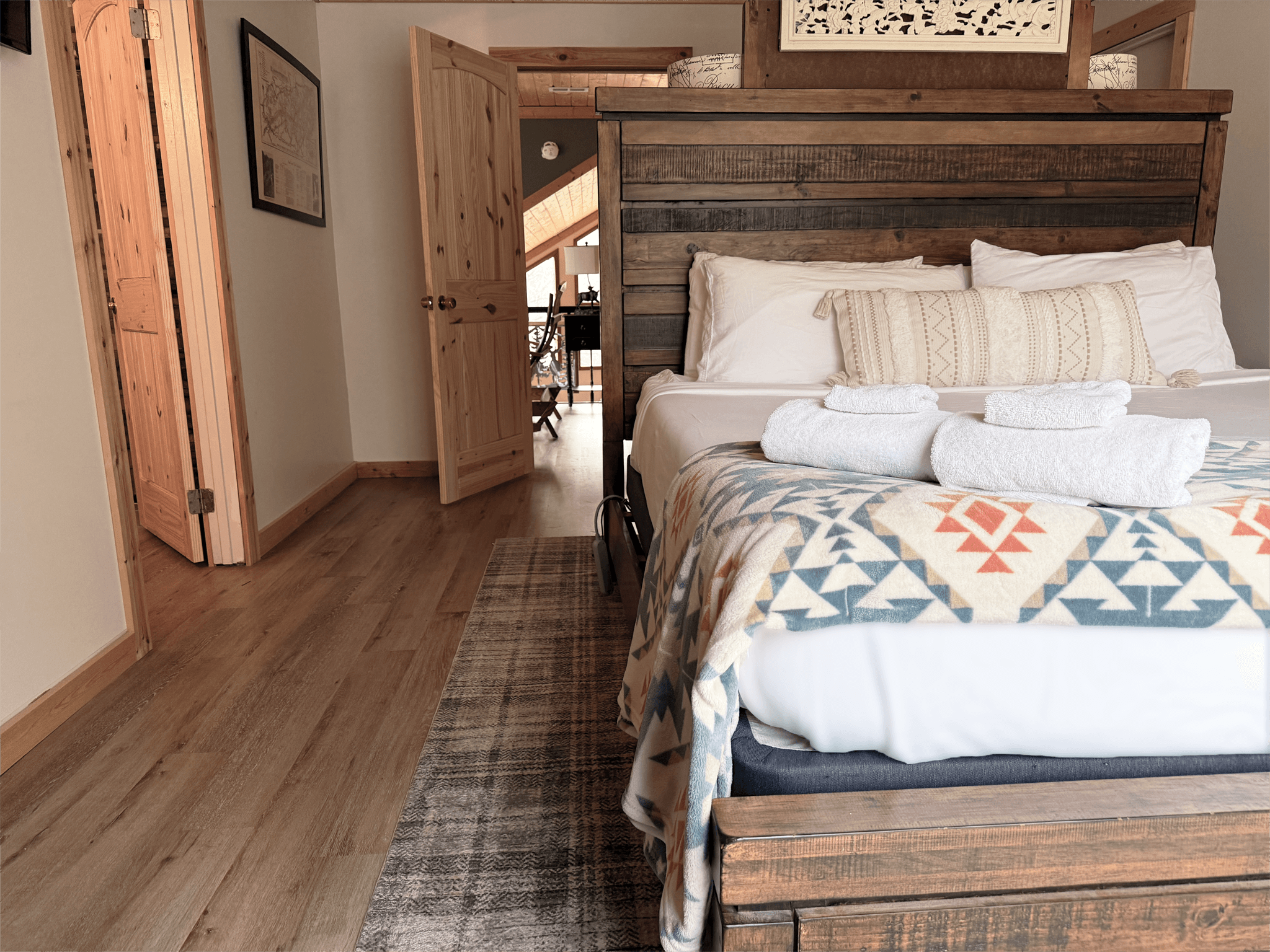Spacious master bedroom in The Teddy with a king-sized log bed, luxury linens, and private access to the balcony at Frontier Hall.