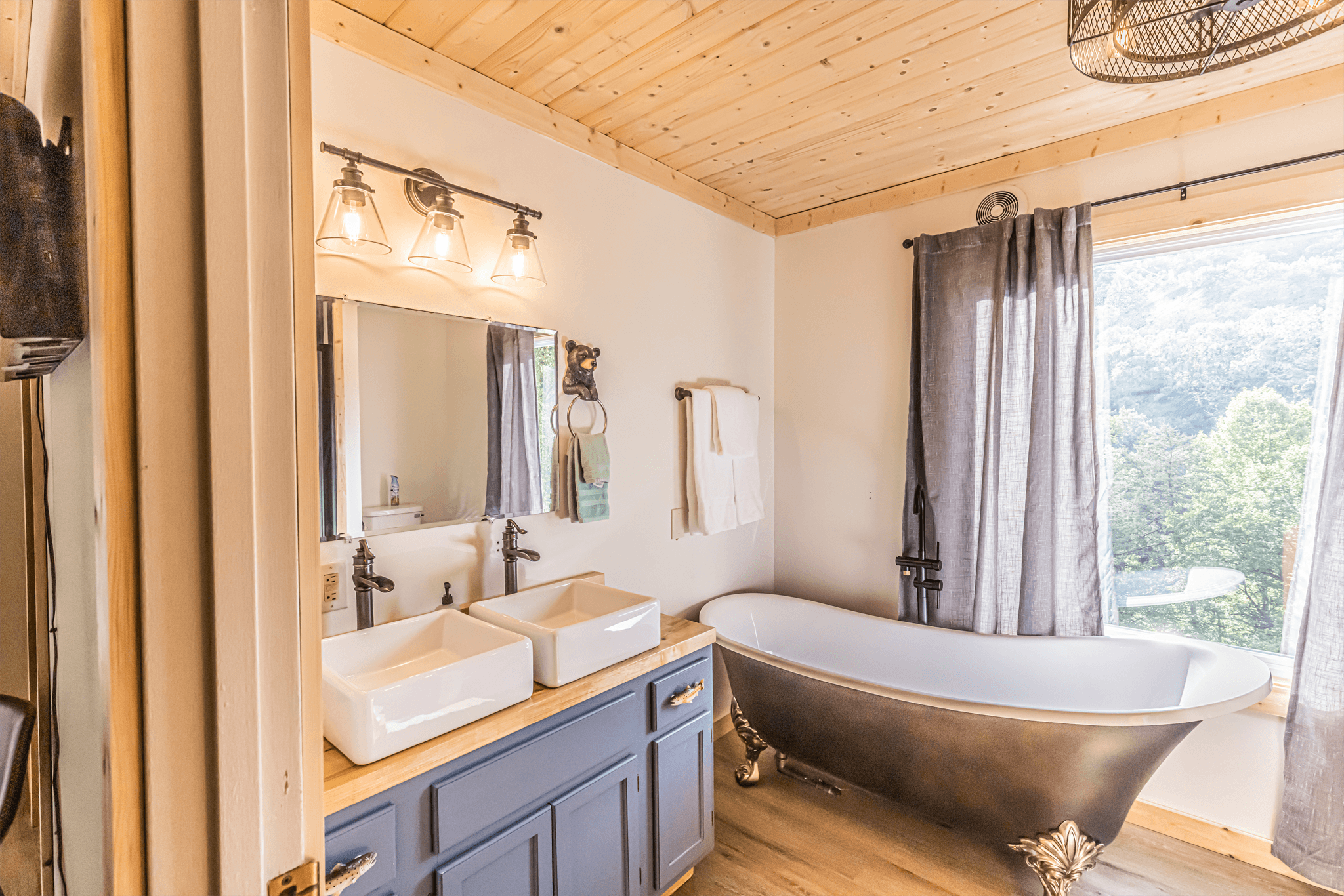 Luxury master bathroom in The Teddy featuring a white clawfoot soaking tub positioned in front of a window with views of the North Carolina mountains.