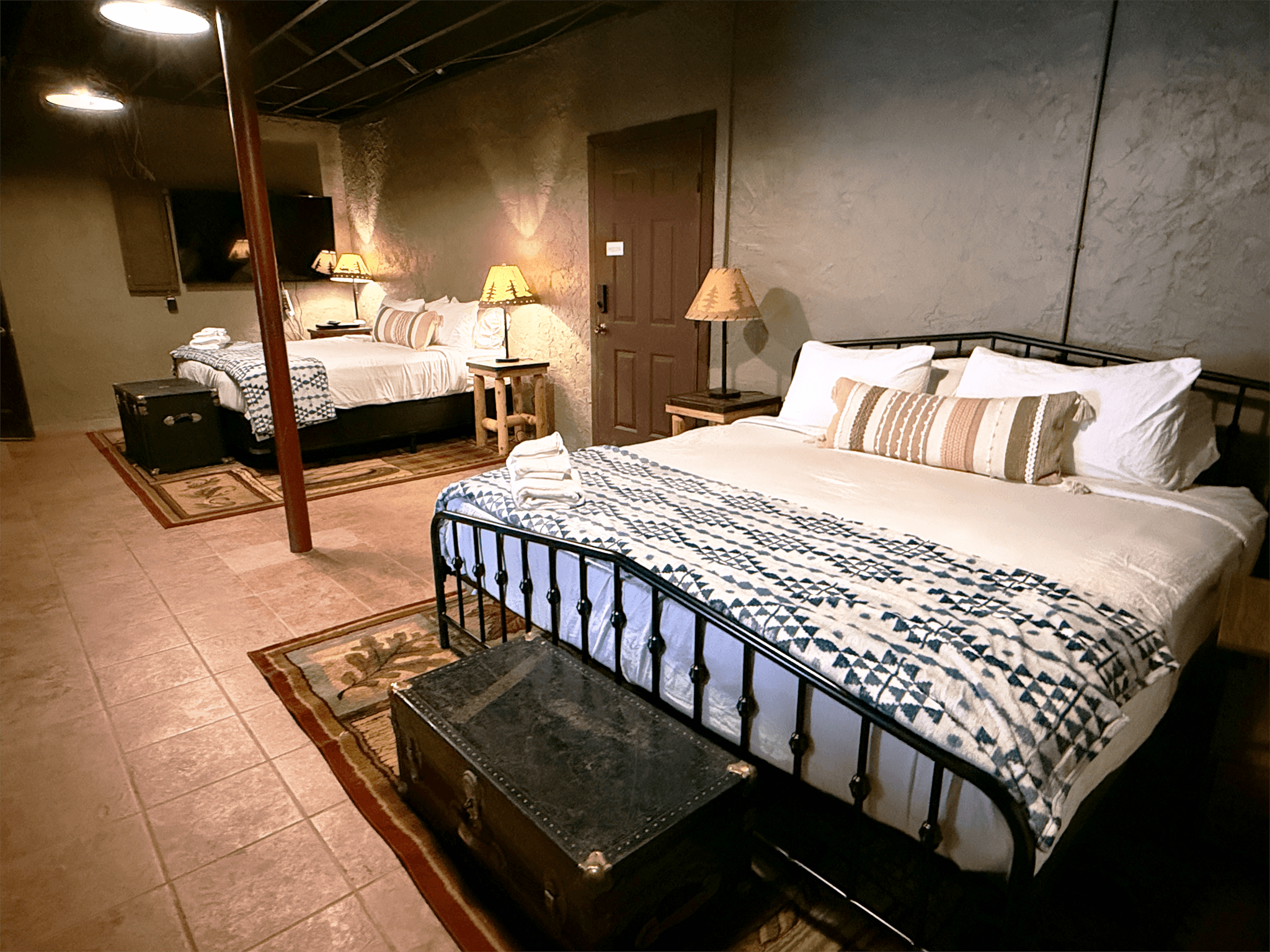 Lewis and Clarke camp guest bedroom at The Teddy featuring American explorer-themed decor, a king-sized bed, and views of the surrounding woods