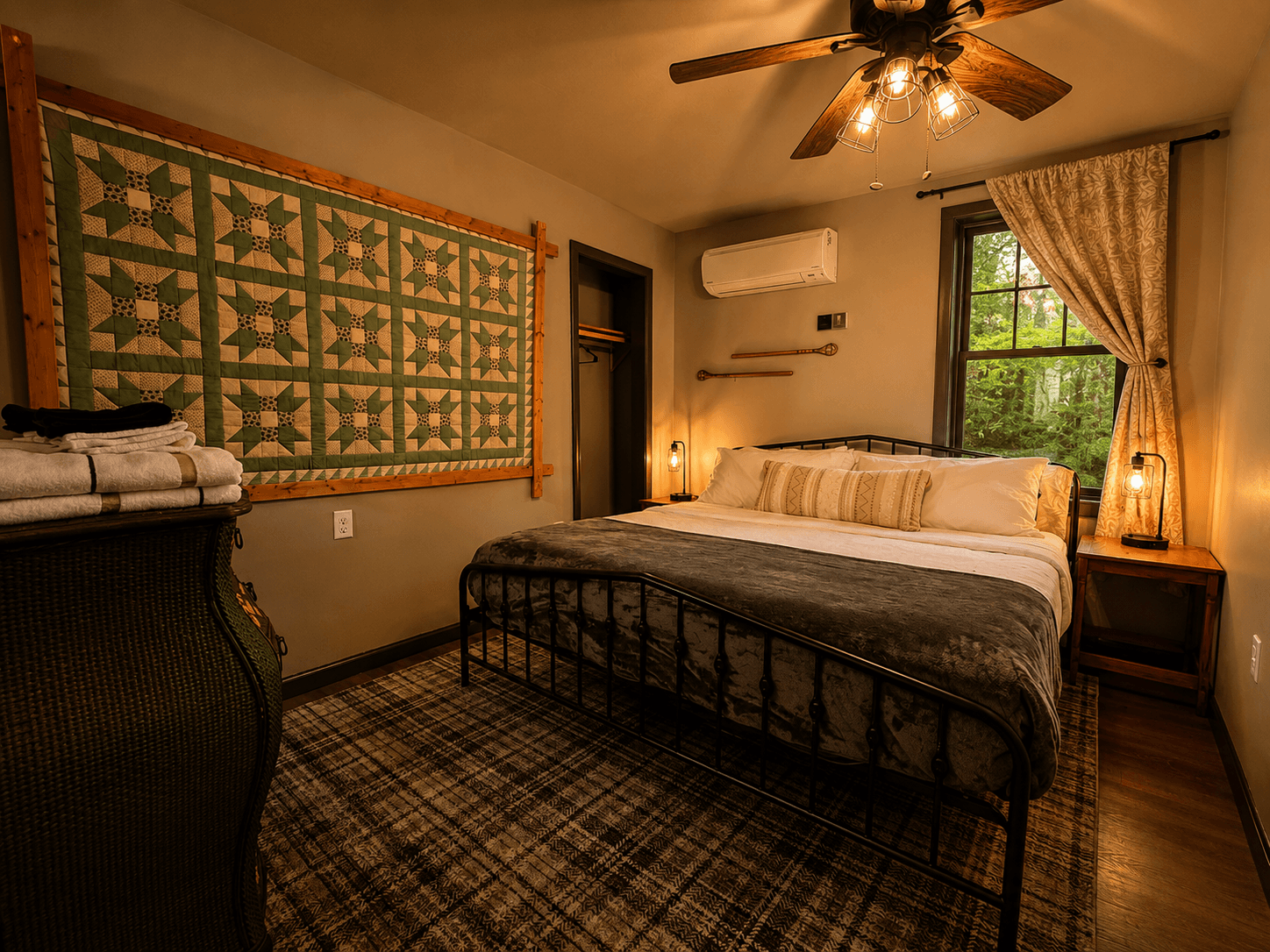 Cozy bedroom featuring a quilted wall hanging, a wrought iron bed, and large windows.