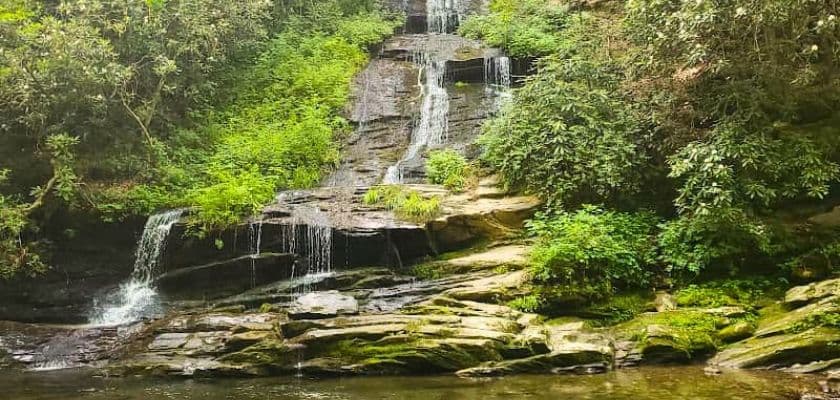 A serene waterfall cascading down mossy rocks, surrounded by lush greenery.