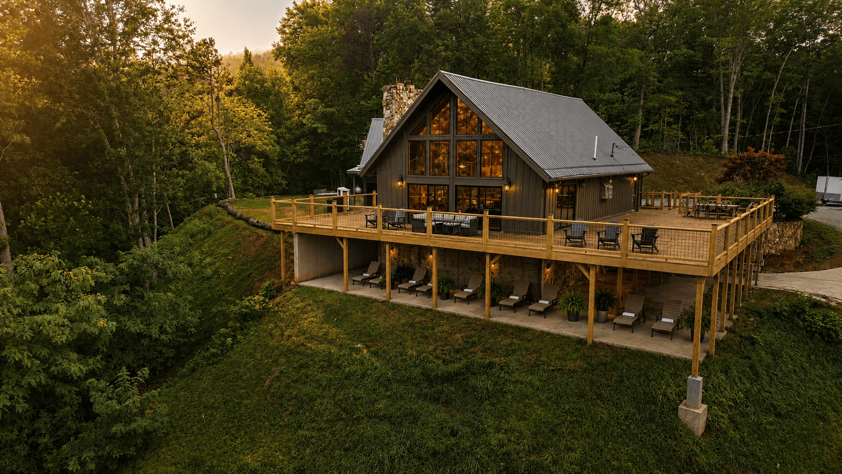 A modern cabin with a large wooden deck surrounded by lush forest.