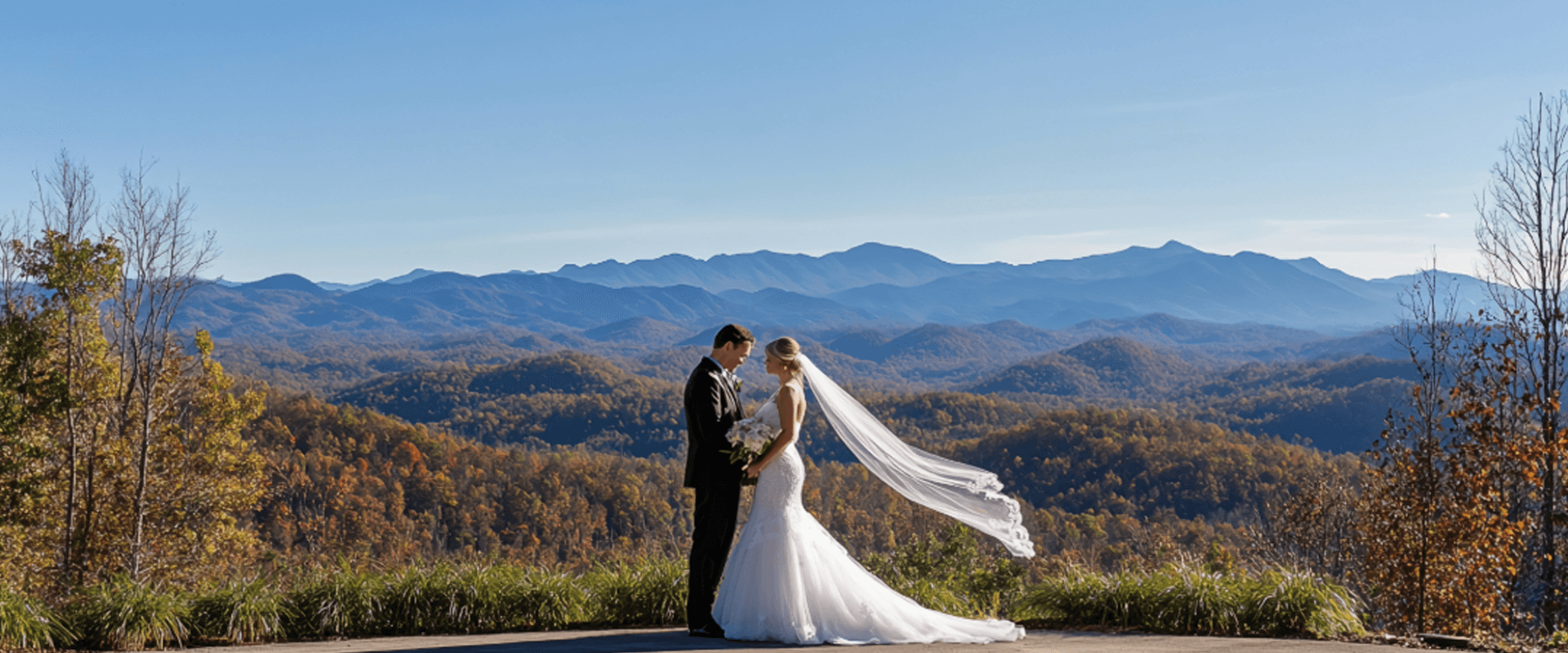 A bride and groom stand together with a sweeping mountain landscape in the background.