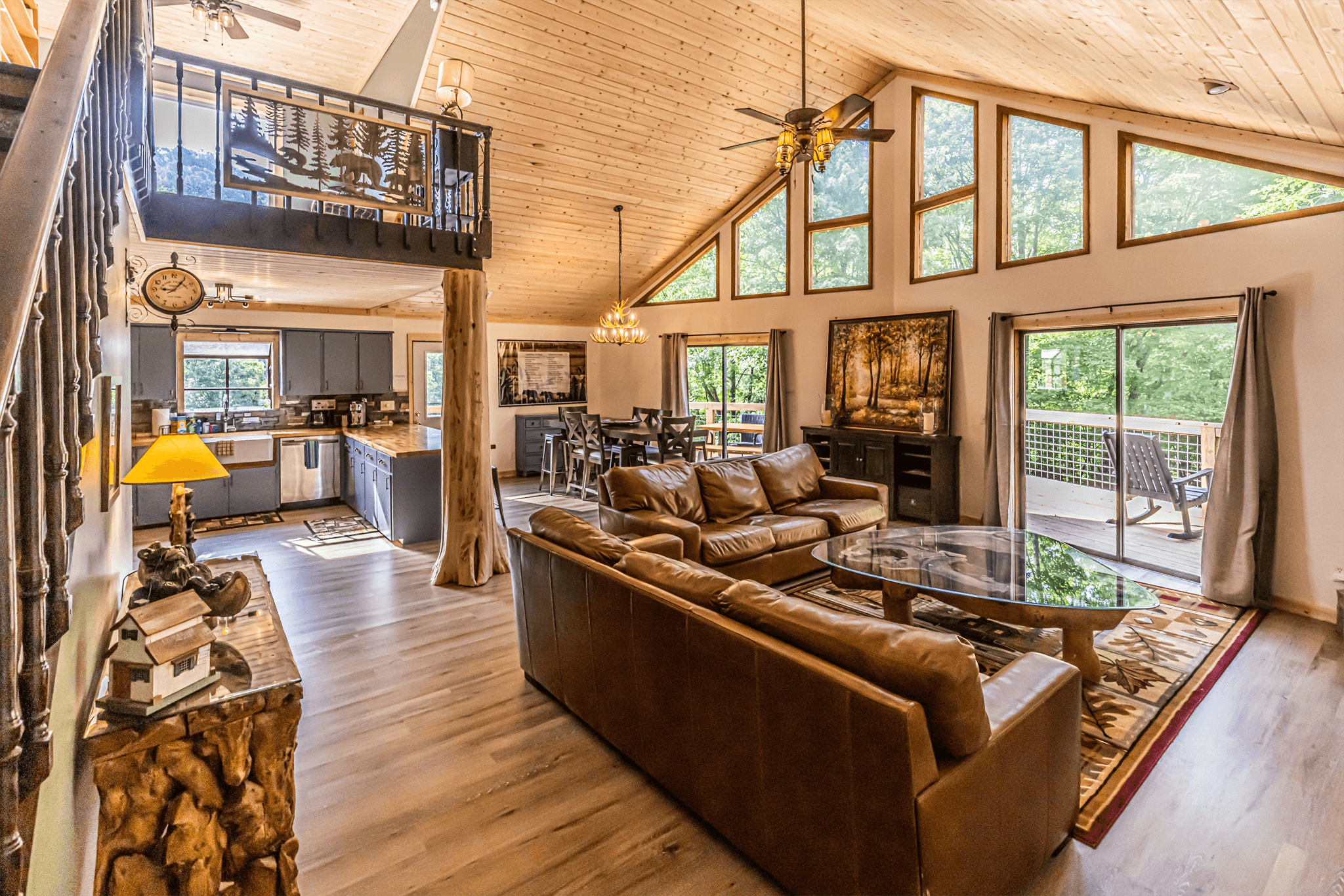 Cozy living room at The Teddy featuring a stone fireplace, leather sofas, and large windows overlooking the Smoky Mountains.