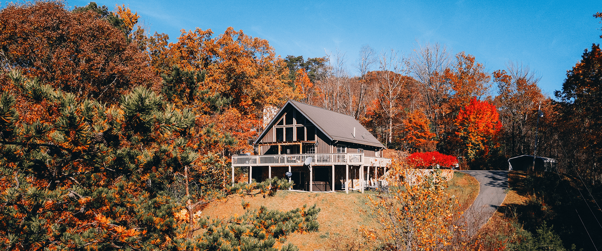 A large, rustic house surrounded by vibrant autumn foliage.