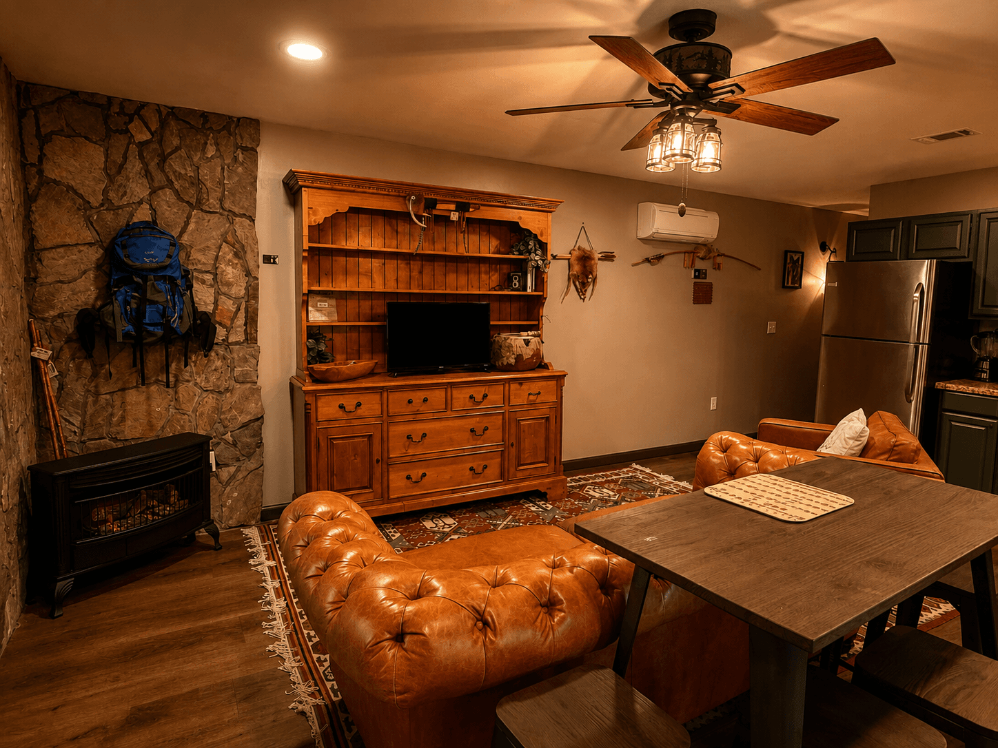 Cozy living area featuring a leather sofa, wooden storage unit, dining table, and warm lighting.