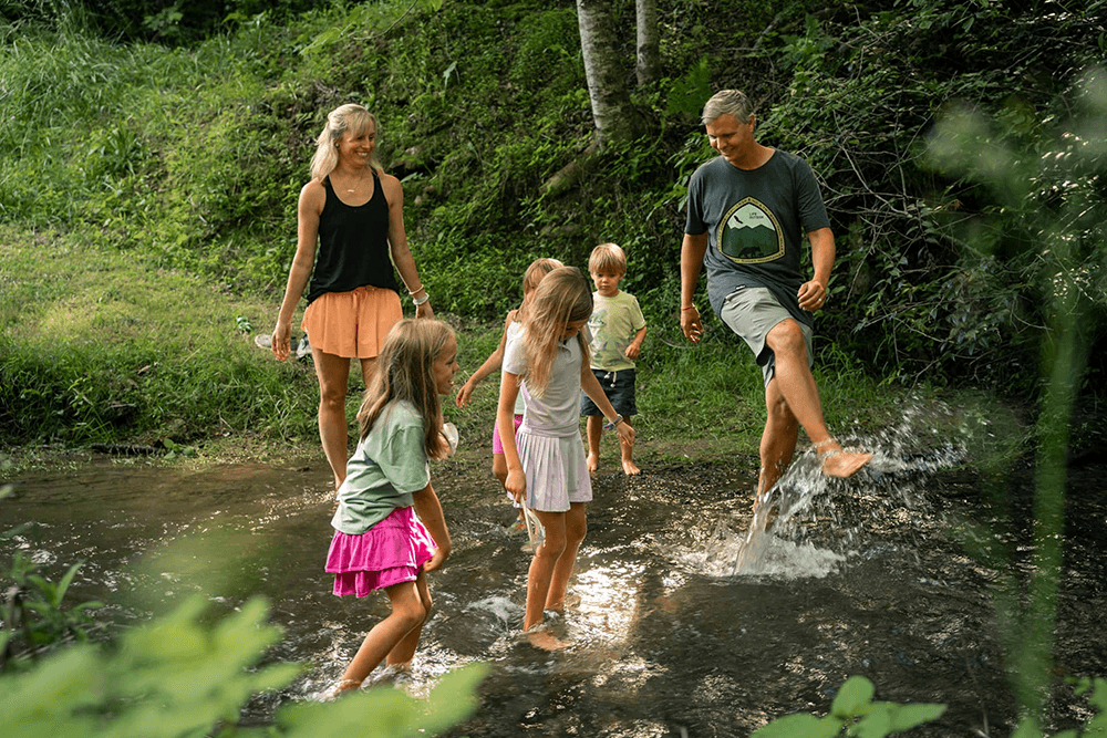 A family enjoys splashing in a shallow stream on a sunny day.