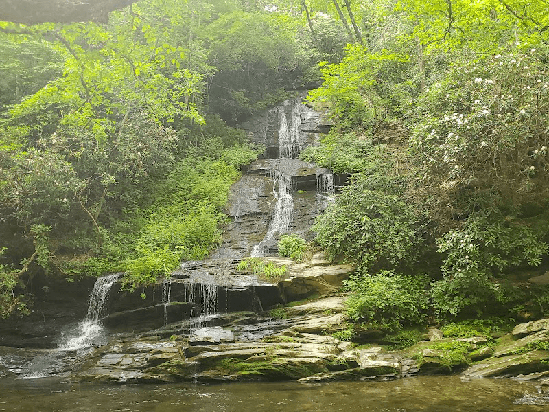 A serene waterfall cascading over rocky terrain, surrounded by lush greenery.