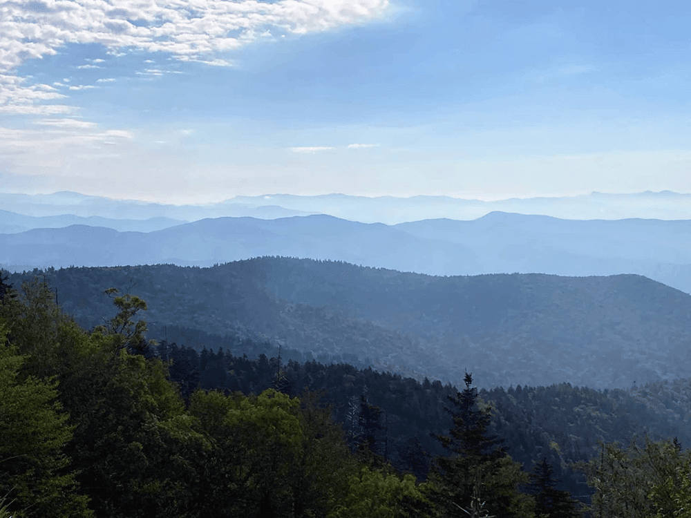 A panoramic view of misty blue mountains under a cloudy sky.